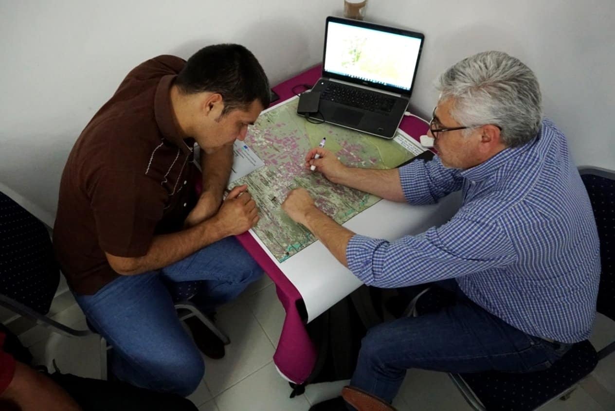Taguide Picanerai, of the Ayoreo Totobiegosode people, and member of the Organización Payipie Ichadie Totobiegosode (​OPIT), together with Jorge Acuña, GIS technician, of the organization Gente Ambiente y Territorio (GAT), comparing paper and digital maps of the Chaco.